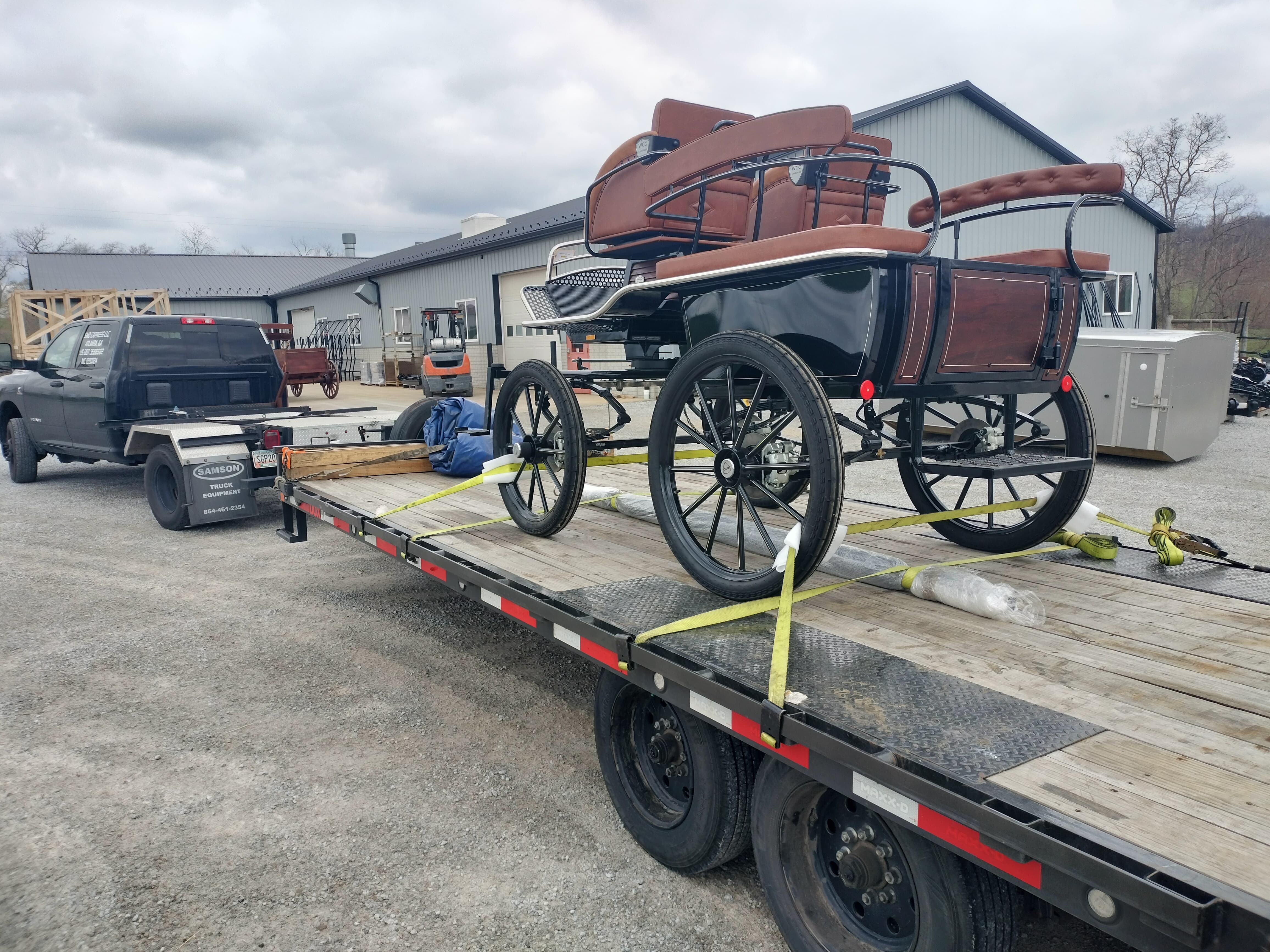 black Ram truck pulling a hotshot trailer loaded with an old-fashioned carriage