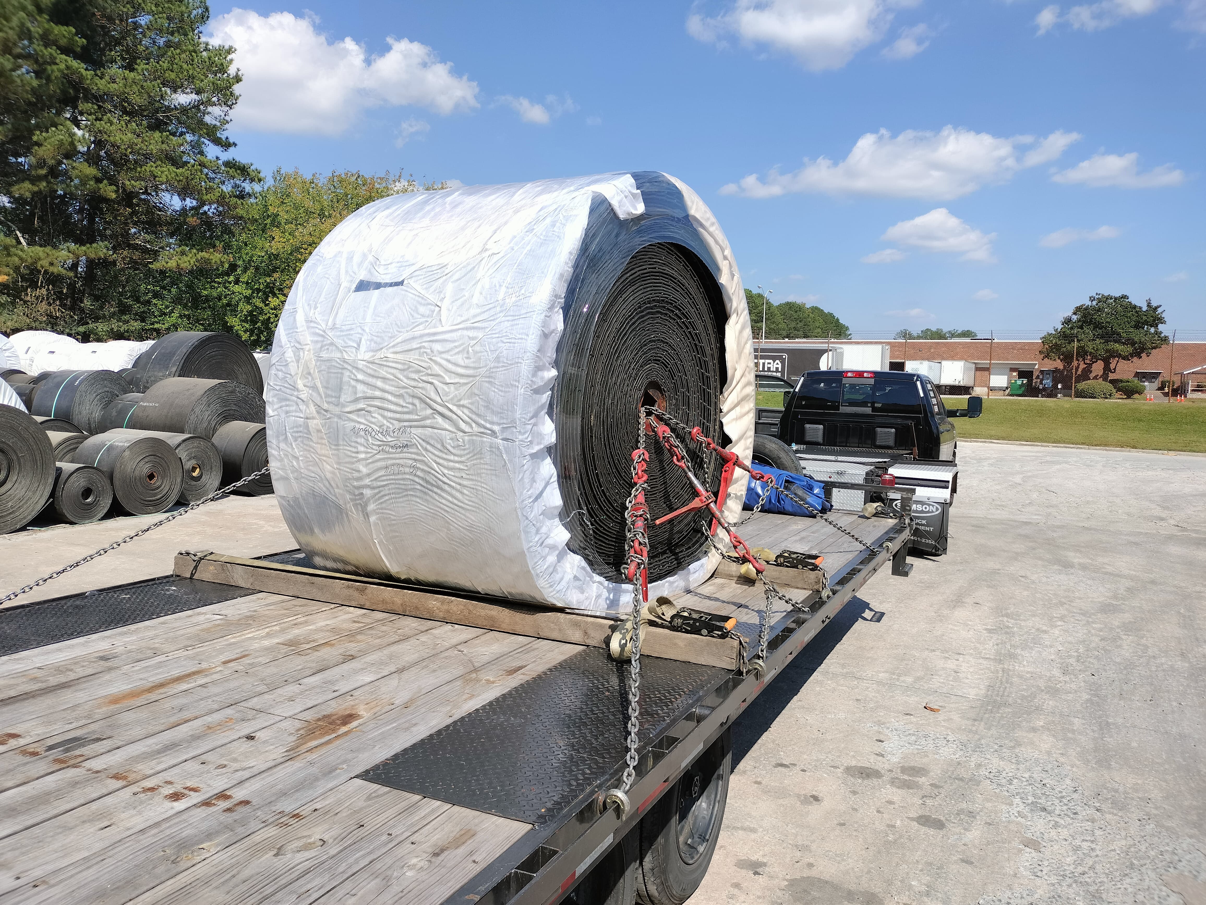 a hotshot trailer loaded with an industrial-size spool of a dark gray material