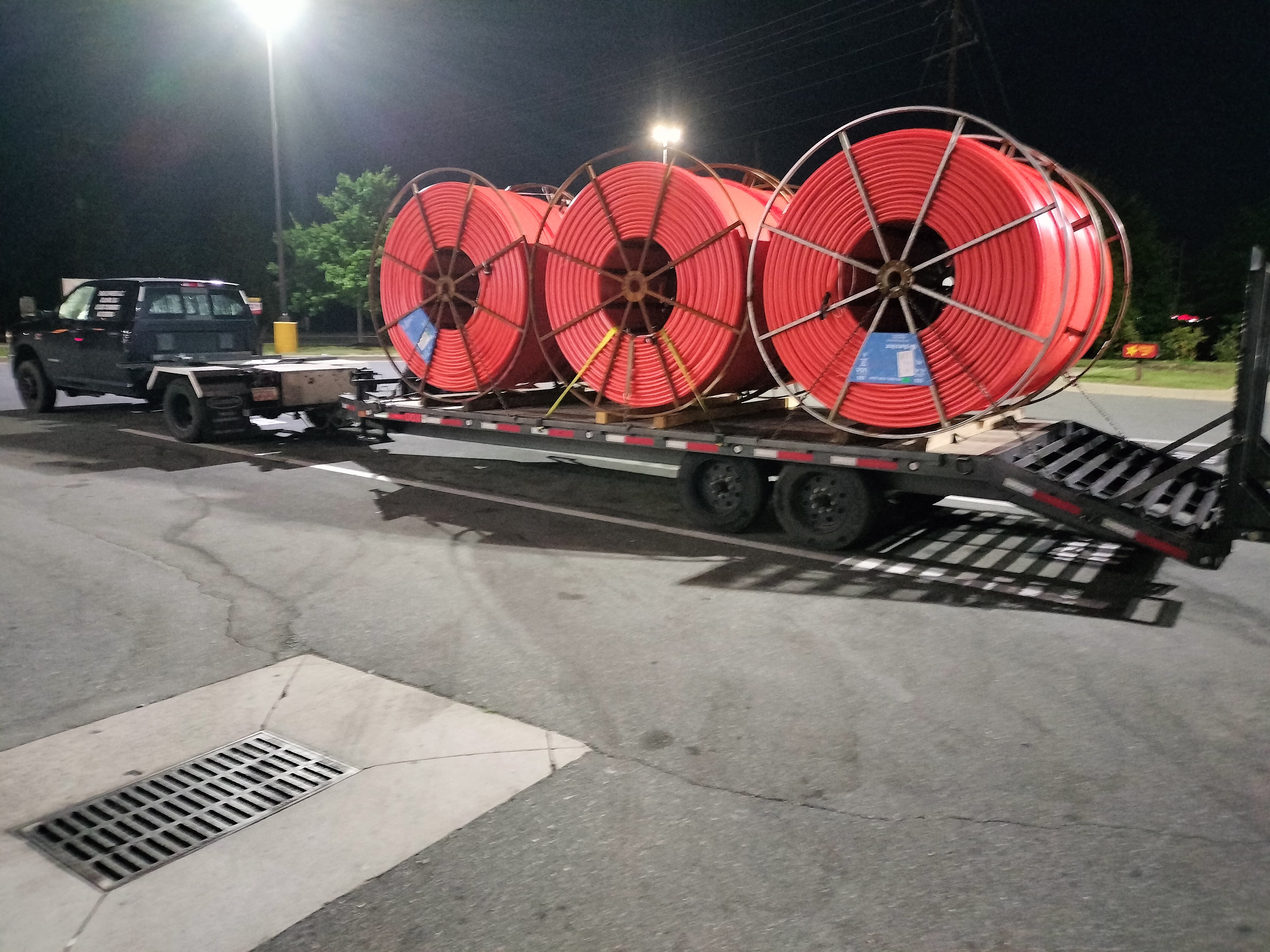 black Ram truck pulling a hotshot trailer loaded with industrial-size spools of a synthetic red material